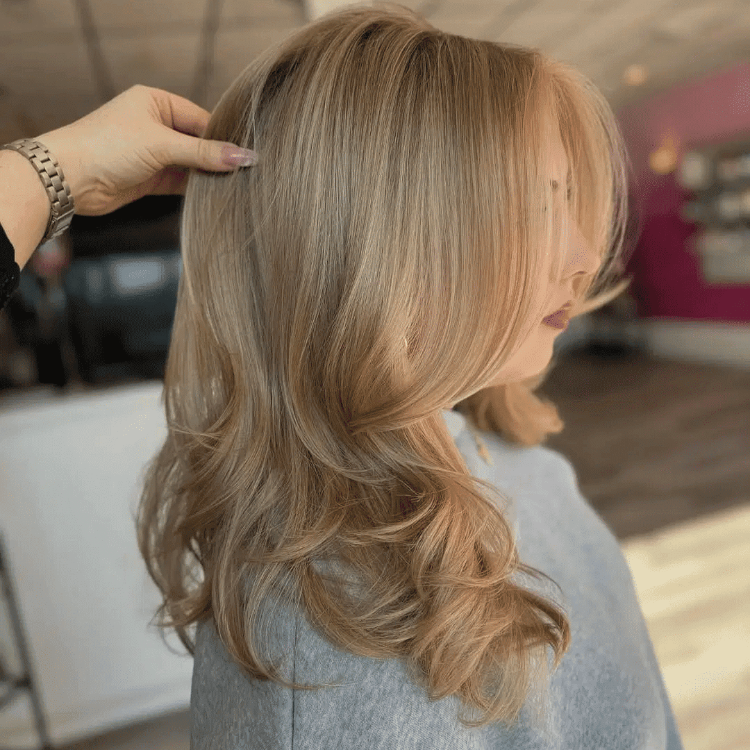 Woman with freshly styled, shoulder-length blonde hair in a salon.